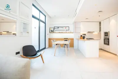 a kitchen and living room with a table and chairs at Blue Breeze - Elegant 1BR with Private Jacuzzi & Terrace in JVC in Dubai