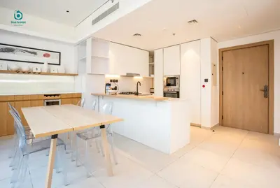 a kitchen with white cabinets and a wooden table at Blue Breeze - Elegant 1BR with Private Jacuzzi & Terrace in JVC in Dubai