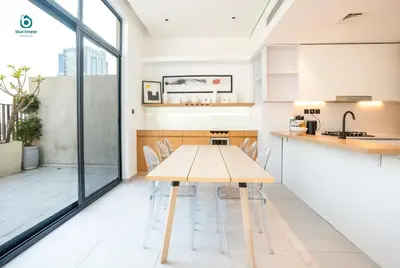 a kitchen and dining room with a wooden table and chairs at Blue Breeze - Elegant 1BR with Private Jacuzzi & Terrace in JVC in Dubai