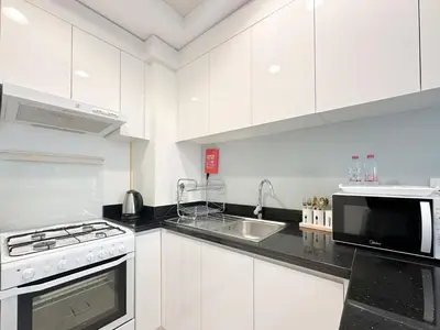 a white kitchen with a microwave and a sink at Bespoke Holiday Homes - High floor studio in Tower 108 JVC in Dubai