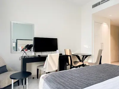 a bedroom with a bed and a desk with a television at Bespoke Holiday Homes - High floor studio in Tower 108 JVC in Dubai