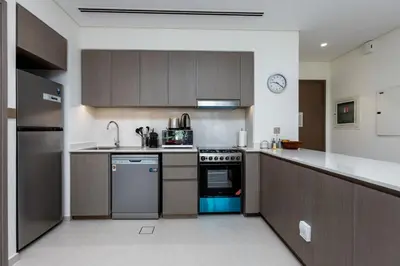 a kitchen with brown cabinets and a blue oven at Brand New 1BR Apt in Grande Residence, Downtown Dubai - Allsopp & Allsopp in Dubai