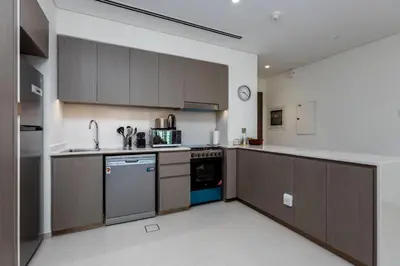 a kitchen with wooden cabinets and a stove top oven at Brand New 1BR Apt in Grande Residence, Downtown Dubai - Allsopp & Allsopp in Dubai