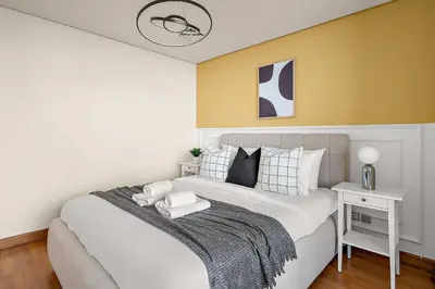 a bedroom with a large bed with a yellow wall at Silkhaus Sky Gardens at Homestyle Studio in DIFC in Dubai