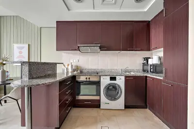 a kitchen with wooden cabinets and a washer and dryer at Silkhaus Sky Gardens at Homestyle Studio in DIFC in Dubai