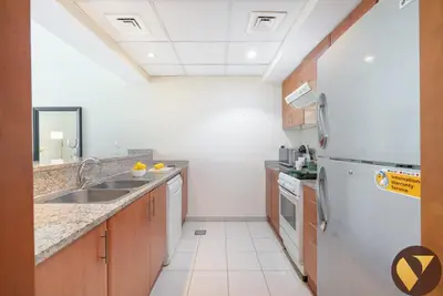 a kitchen with a sink and a refrigerator at Vogue The Greens Al Dhafrah near Mall of the Emirates, One Bedroom Apartment with Balcony and vibrant community view, Access to all Amenities in Dubai