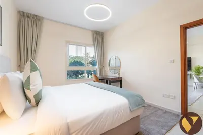 a bedroom with a large bed and a window at Vogue The Greens Al Dhafrah near Mall of the Emirates, One Bedroom Apartment with Balcony and vibrant community view, Access to all Amenities in Dubai