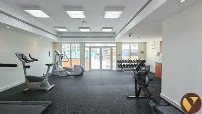 a gym with several treadmills and machines in a room at Vogue The Greens Al Dhafrah near Mall of the Emirates, One Bedroom Apartment with Balcony and vibrant community view, Access to all Amenities in Dubai