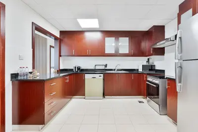 a large kitchen with wooden cabinets and appliances at Savis Home Oceanfront Serenity and Marina Views in Dubai