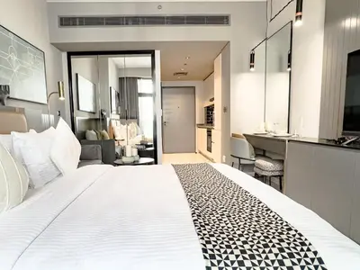 a bedroom with a large white bed and a kitchen at Select Stay-Studio in MAG 318 - Minutes to Dubai Mall in Dubai