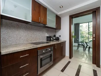 a kitchen with wooden cabinets and a counter top at Bright 1-Bedroom with Marina Infinity Pool in Dubai