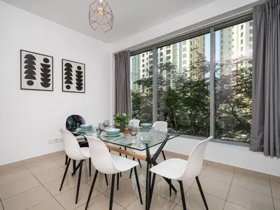 a dining room with a glass table and white chairs at Bright 1-Bedroom with Marina Infinity Pool in Dubai