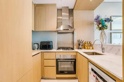 a kitchen with wooden cabinets and a stove top oven at 2 Bedrooms with Iconic Burj Khalifa Views Stay in Dubai