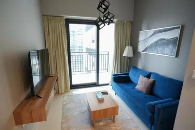 a living room with a blue couch and a tv at Luxurious Pool View 1BHK, Zada Tower in Dubai