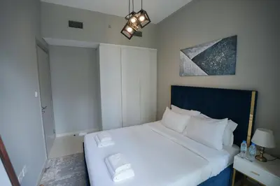 a bedroom with a white bed with a blue headboard at Luxurious Pool View 1BHK, Zada Tower in Dubai