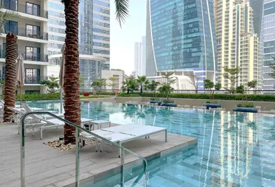 a large swimming pool with palm trees and buildings at Luxurious Pool View 1BHK, Zada Tower in Dubai