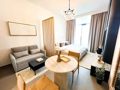 a living room with a couch and a bed and a table at Modern Studio in JVC - Pool, Gym & BBQ Access in Dubai