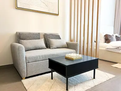 a living room with a couch and a coffee table at Modern Studio in JVC - Pool, Gym & BBQ Access in Dubai