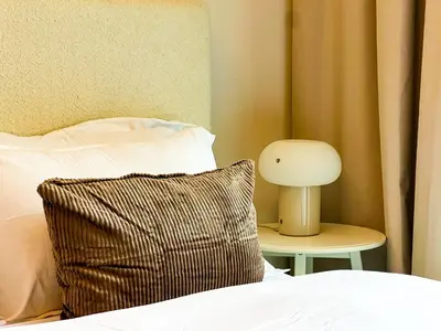 a bed with a pillow and a lamp on a table at Modern Studio in JVC - Pool, Gym & BBQ Access in Dubai