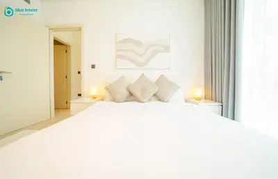 a white bedroom with a large bed with pillows at Blue Breeze - Modern Apt with Partial Marina Views & Balcony in Dubai