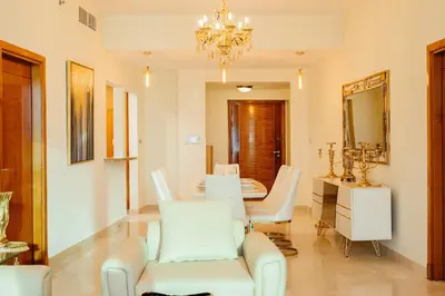 a living room with a table and chairs and a chandelier at SettlerHomes - FIRST CLASS JBR Stay On High-Floor in Dubai