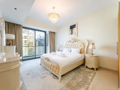 a bedroom with a large bed and a chandelier at SettlerHomes - FIRST CLASS JBR Stay On High-Floor in Dubai