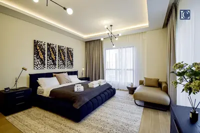 a bedroom with a large bed and a chair at Luxury Escapes - Three-Bedroom Apartment with Lake View in Dubai