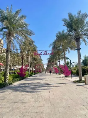 a walkway with palm trees in a resort at Great one bedroom apartment with infinity pool in Dubai