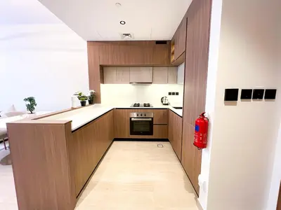 a kitchen with wooden cabinets and a red fire extinguisher at Stylish 1-Bedroom Retreat in Prime Gardens , Arjan in Dubai