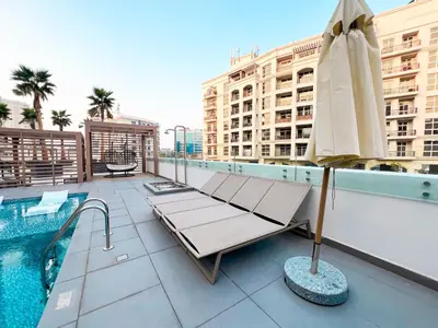 a patio with a pool and a umbrella on a building at Stylish 1-Bedroom Retreat in Prime Gardens , Arjan in Dubai