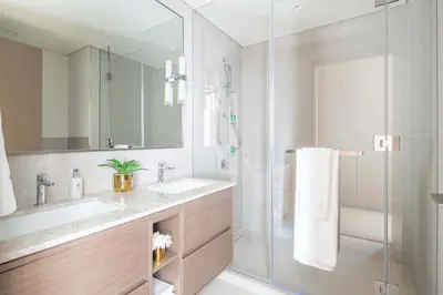a bathroom with two sinks and a glass shower at Frank Porter - Grande Residence in Dubai