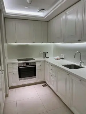 a white kitchen with white cabinets and a sink at Apt Dubai Downtown in Dubai