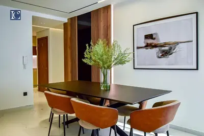 a dining room table with chairs and a vase of flowers at Luxury Escapes - Luxurious 2-Bedroom Apartment with Stunning Lake Views in JBR in Dubai