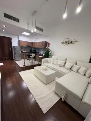 a living room with a white couch and a kitchen at Brand New Apartment IN JVC in Dubai