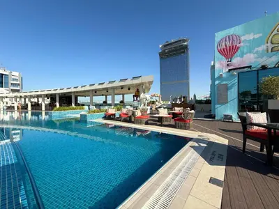 a swimming pool with tables and chairs on a building at Studio Apartment in Seven Palm with Beach Access in Dubai