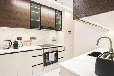 a kitchen with white counters and wooden cabinets at Marina Sea View,Elegant and Spacious - High Floor in Dubai