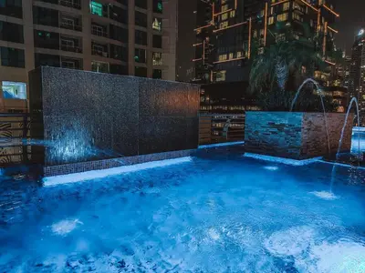 a swimming pool with a fountain in a city at night at Marina Sea View,Elegant and Spacious - High Floor in Dubai