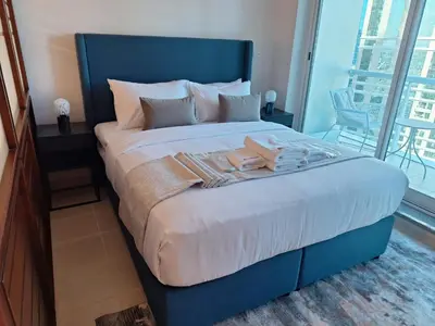 a large bed with a blue headboard in a bedroom at Bright Studio Unit at Lake Terrace with lake view in Dubai