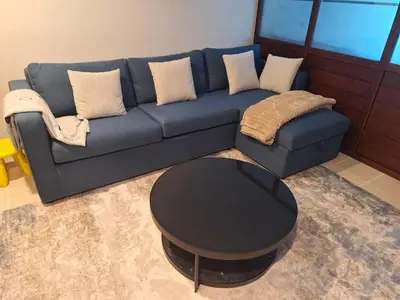 a blue couch with a table in a living room at Bright Studio Unit at Lake Terrace with lake view in Dubai