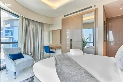 a bedroom with a white bed and a blue chair at bnbmehomes - DAMAC Towers Paramount in Dubai