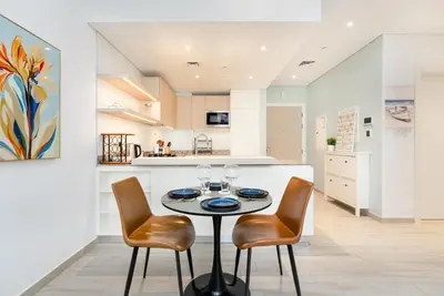 a kitchen with a table and two chairs and a counter at Ahlan HH - Beautiful 1BR Home with Pool View - Belgravia III, JVC in Dubai