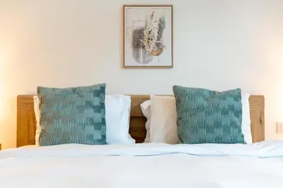 a bedroom with a bed with two green pillows at Ahlan HH - Beautiful 1BR Home with Pool View - Belgravia III, JVC in Dubai