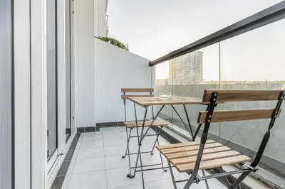 a balcony with a wooden table and chairs on it at Trendy Fully Equipped Beautiful Apartment for Four near to Metro in Dubai