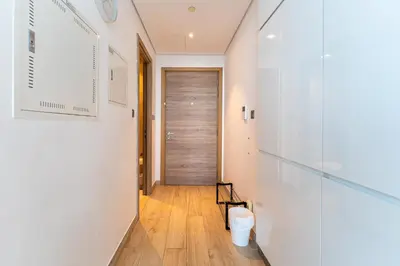 a hallway with white walls and a wooden door at Cozy Marina Studio with Partial Sea View in Dubai