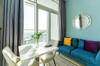 a living room with a blue couch and a table at Cozy Marina Studio with Partial Sea View in Dubai