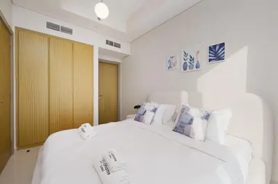 a bedroom with a white bed with blue and white pillows at Aykon Luxury Sky Collection Suites with Sea View by HSHOME in Dubai