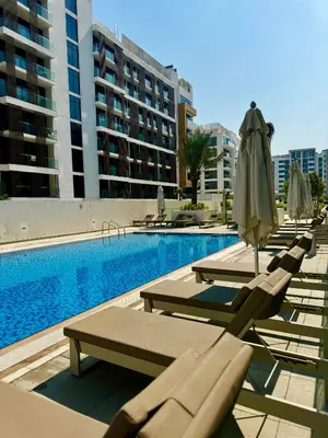a row of lounge chairs and umbrellas next to a swimming pool at 8min from Downtown in Dubai