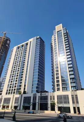 two tall buildings with the sun shining between them at HAVN - 1 Bedroom in Downtown, Burj Khalifa View in Dubai