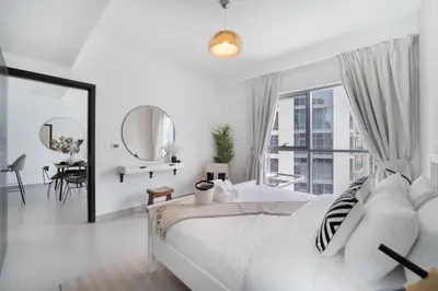 a white bedroom with a large bed and a mirror at HAVN - 1 Bedroom in Downtown, Burj Khalifa View in Dubai