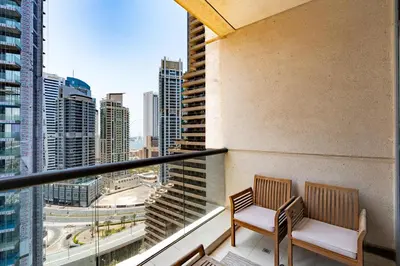 a balcony with two chairs and a view of a city at Vacay Lettings - 1 BHK - Iris Blue Dubai Marina in Dubai
